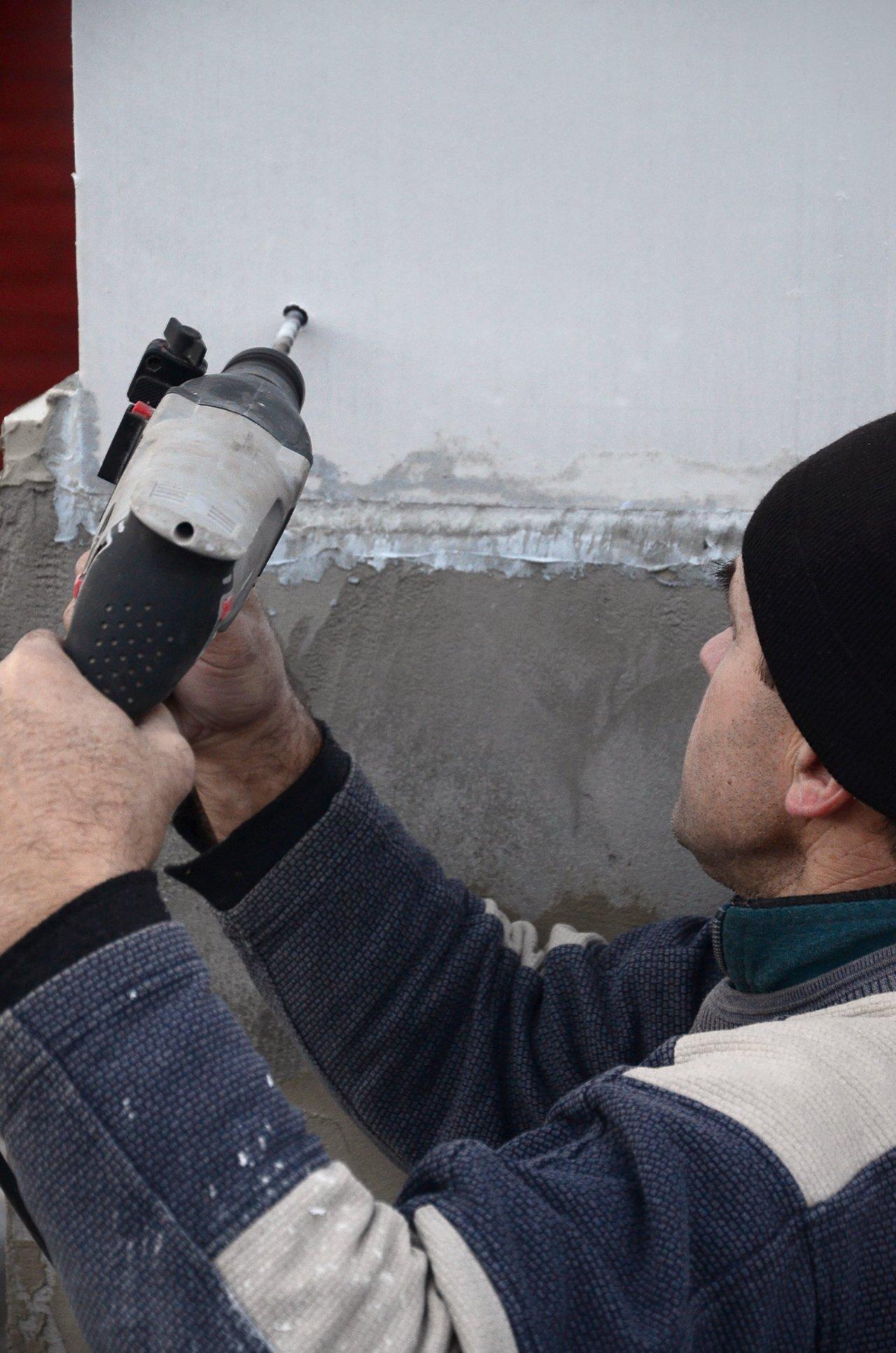 Installation d'isolation par l’extérieur avec bardage sur façade ancienne, mettant en avant la couche isolante en polystyrène.
