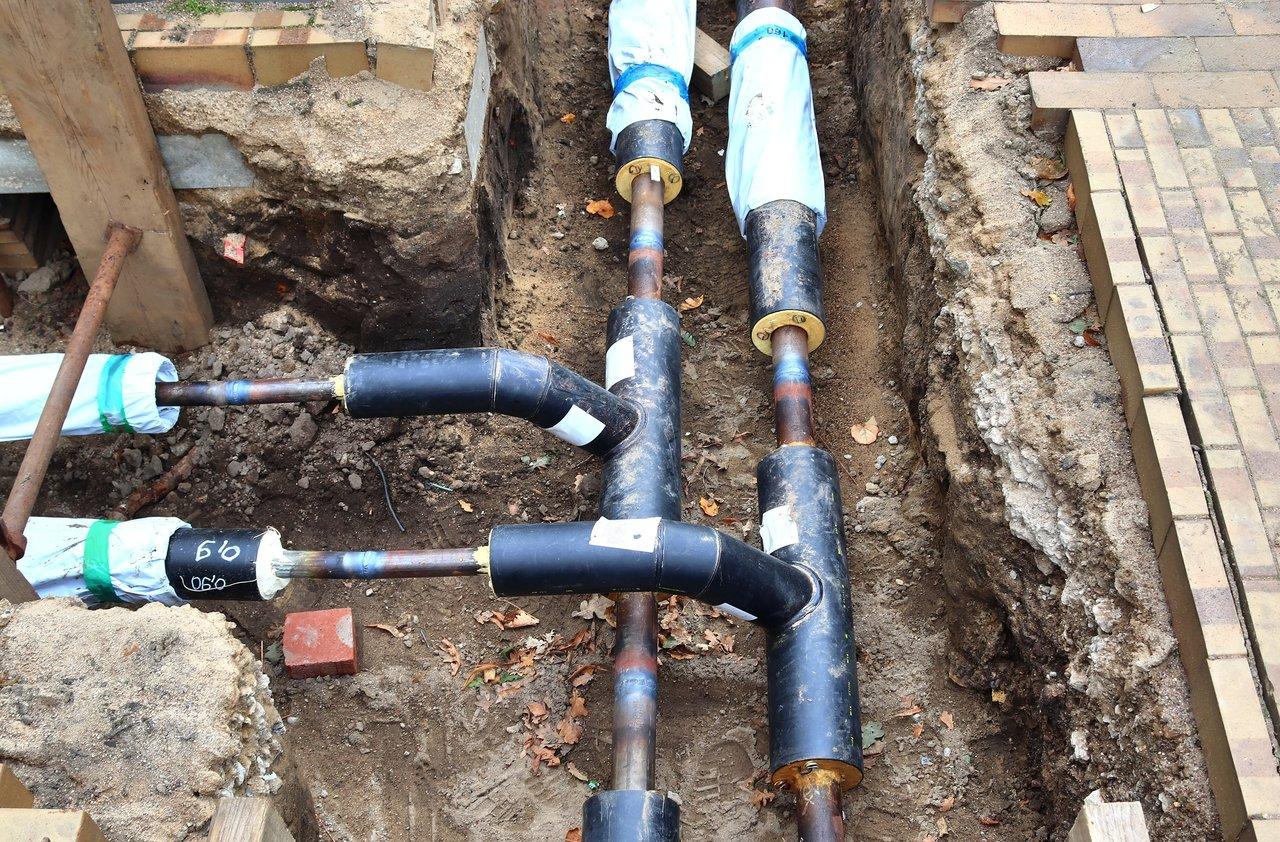 Installation professionnelle d'une pompe à chaleur géothermique dans une maison moderne, avec réseau de tuyaux de chauffage souterrains.