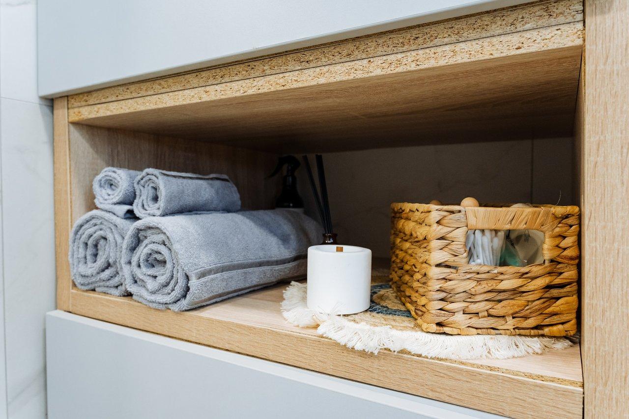Rangement moderne pour salle de bain : élégants rouleaux de serviettes et panier décoratif optimisent l'espace.