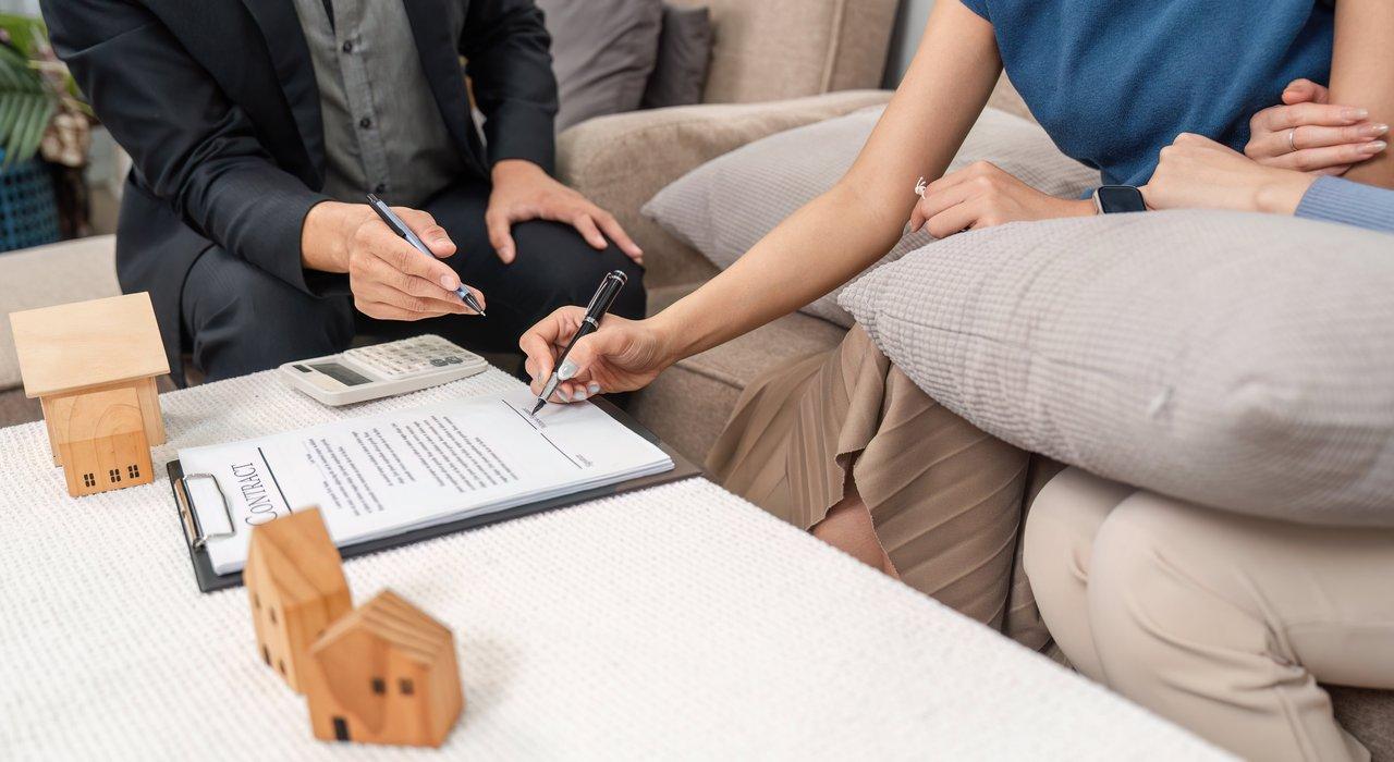Un jeune couple signant un contrat de prêt immobilier, illustrant l'investissement locatif sans apport possible.