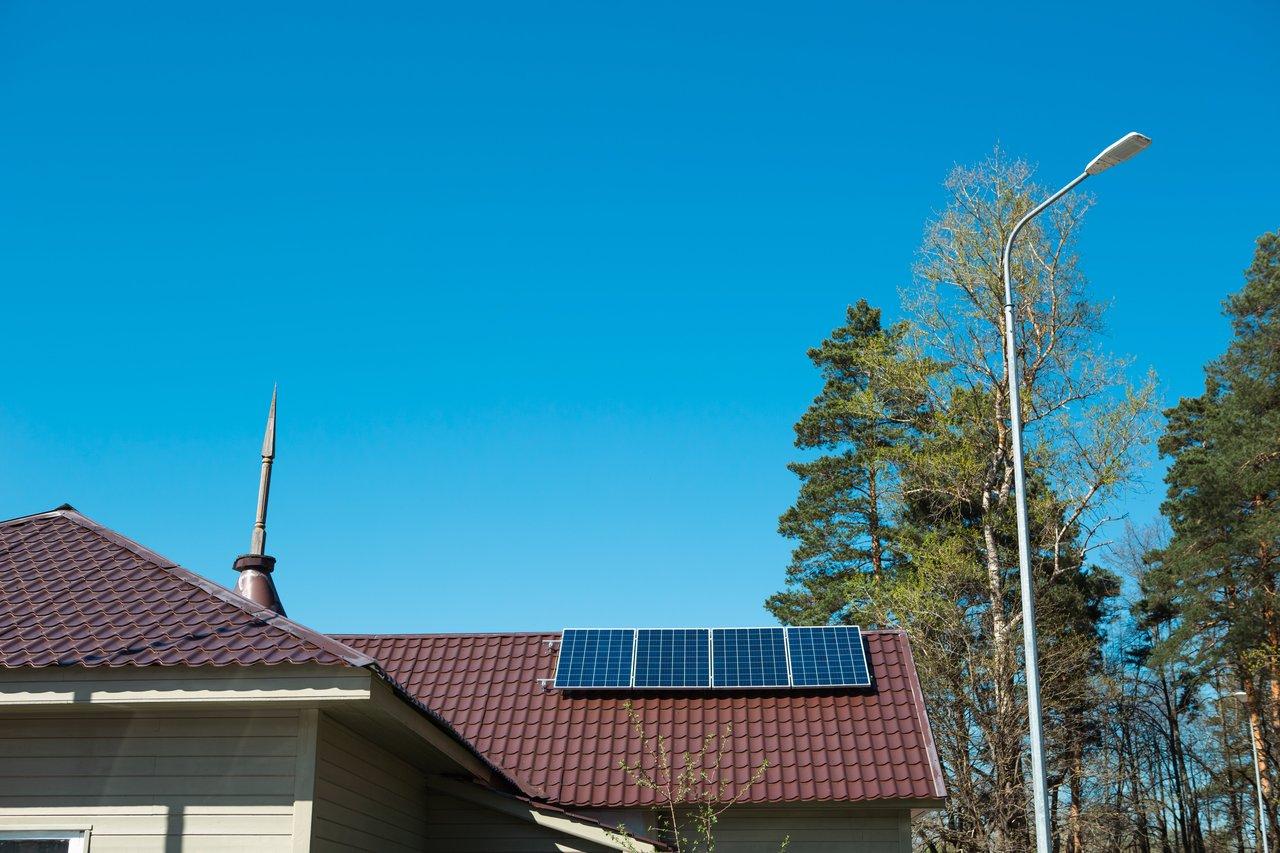 Vue extérieure d’une maison avec jardin équipée de panneaux solaires, symbole de rénovation énergétique et d’énergie alternative.