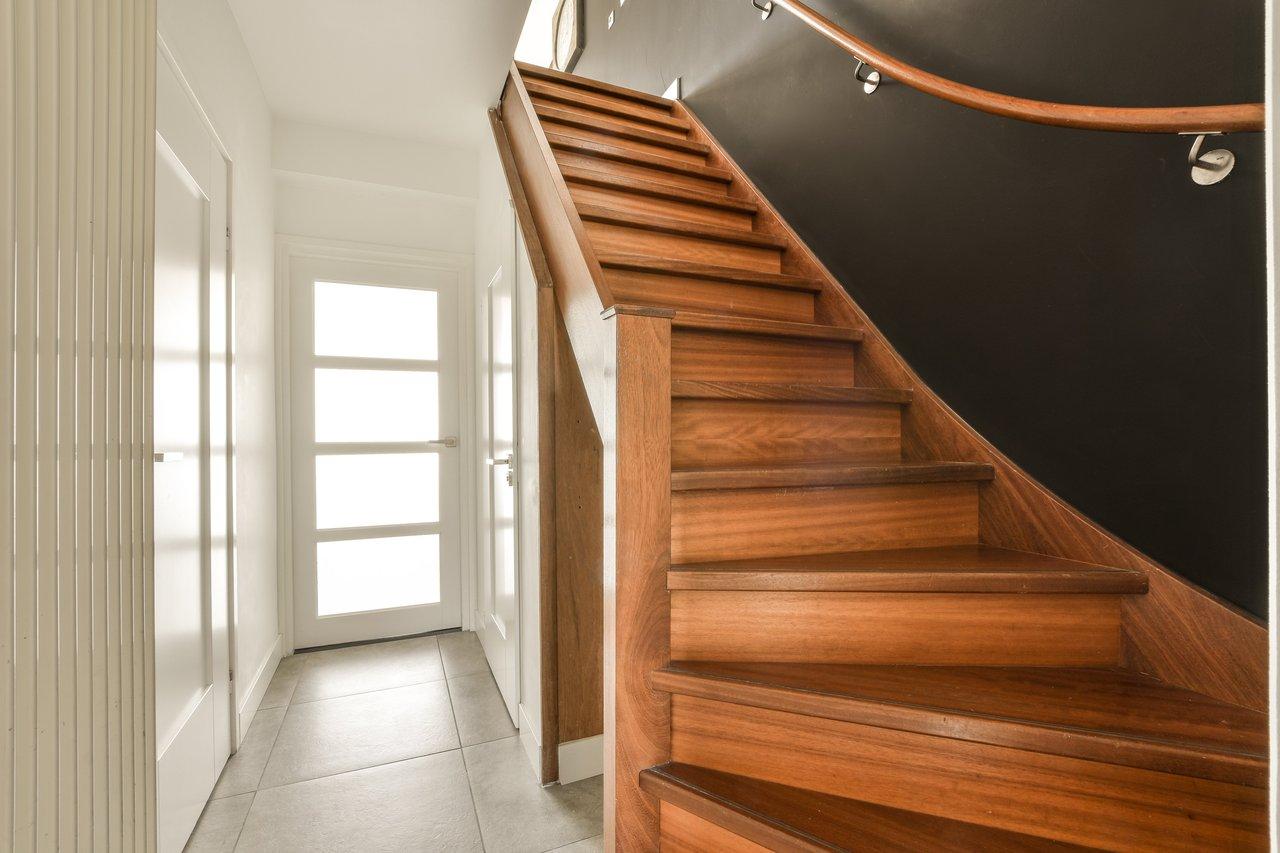 Appartement duplex lumineux avec escalier intérieur en bois et grande fenêtre, offrant un espace moderne et accueillant.