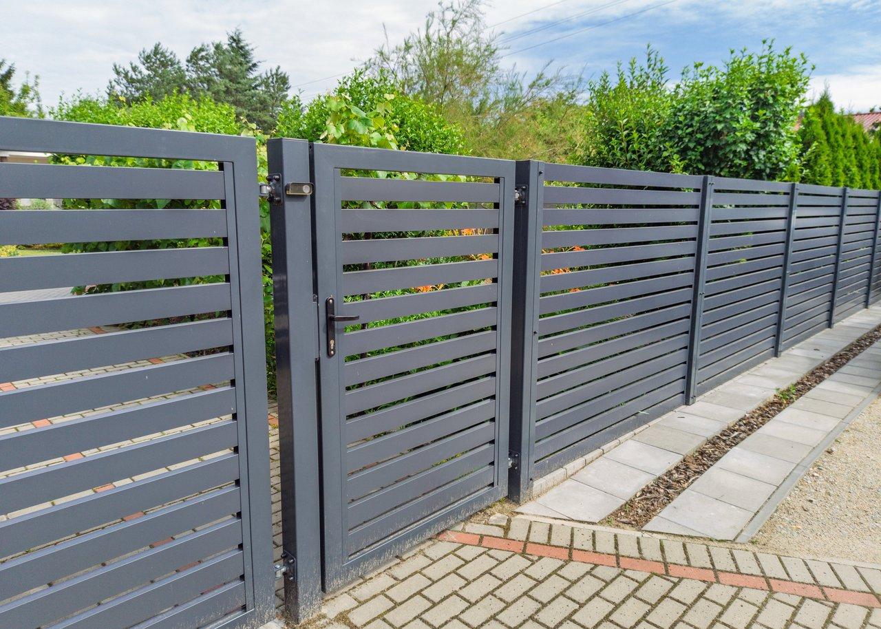 Une clôture moderne en métal avec portail de jardin respectant les normes d'urbanisme en zone résidentielle.