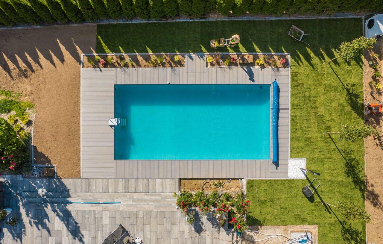 Une piscine creusée contemporaine intégrée dans un jardin harmonieux avec pelouse naturelle.