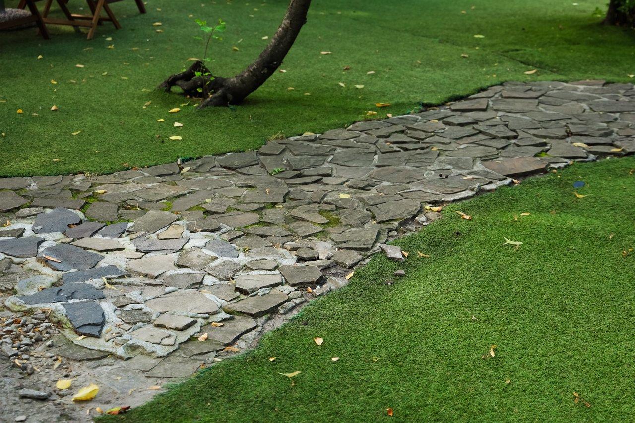 Allée en dalles naturelles dans un jardin méditerranéen facile d’entretien, avec couvre-sol et plantes résistantes.