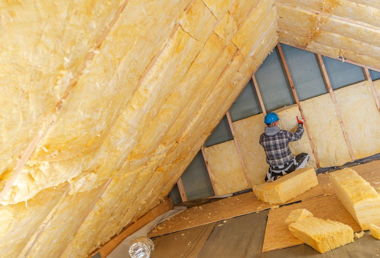 Artisan certifié RGE en train d'effectuer une isolation de toiture pour améliorer l'efficacité énergétique d'une maison en rénovation.