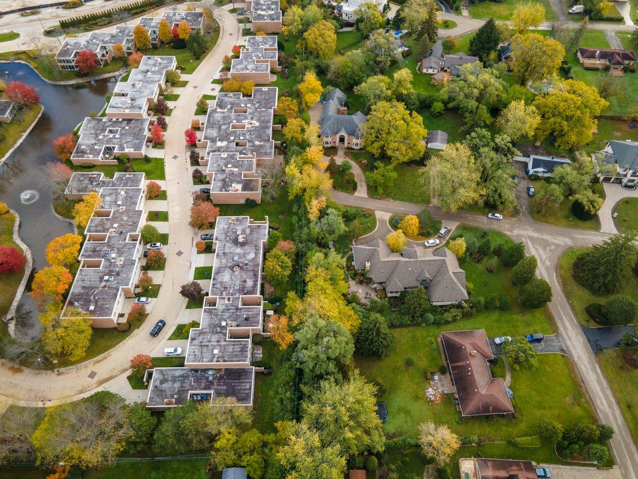 Vue aérienne d’un quartier résidentiel dynamique avec écoles, transports et grands arbres en automne, idéal pour investir.